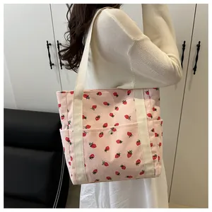 Detailed texture of pink corduroy tote bag with red strawberry print and cream strap