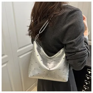 Detail of silver metallic dumpling bag with stud ornaments and wide shoulder strap