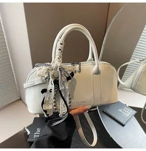 Detalle del bolso Boston blanco crema con lazo de encaje, cinta y dije de perla