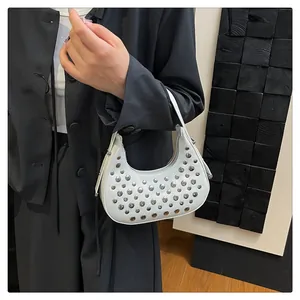 Detail of white moon hobo bag featuring silver metal rivets and sleek zipper closure