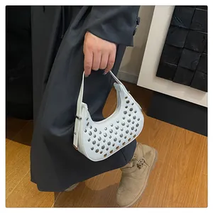Detail of white half-moon bag with silver studs and adjustable leather strap