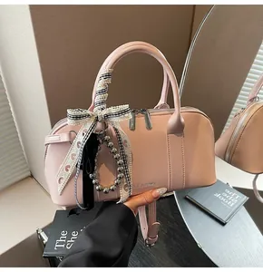 Detalle de bolso Boston de cuero rosa con lazo a cuadros decorativo y colgantes de perlas