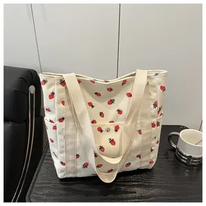 Close-up of strawberry print corduroy tote bag showing front snap pocket and soft texture