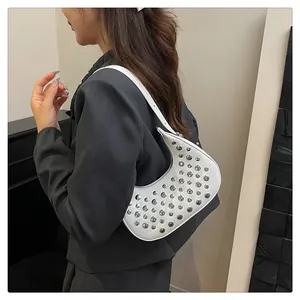 Detailed side view of white crescent shoulder bag with silver studs on a model