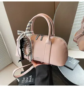 Detalle del bolso de hombro rosa brillante con lazo decorativo y logotipo de Lear K