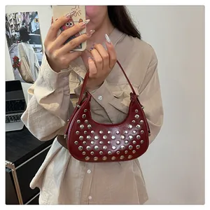 Detailed macro view of dark red moon bag with stylish rows of silver metal rivets