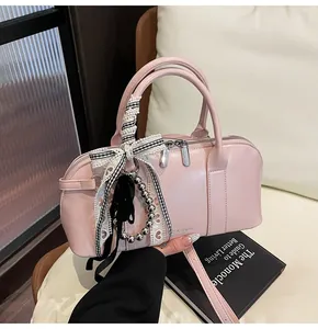 Bolso de charol rosa con colgante de lazo y detalles grabados en un entorno hogareño