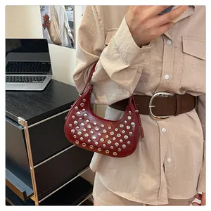 Detail of dark red crescent bag with silver metallic studs and slim shoulder strap