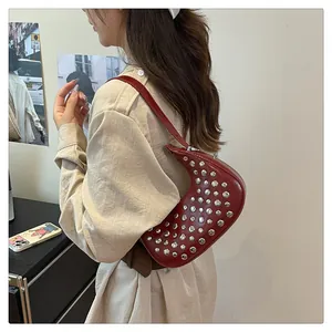 Detail of burgundy moon bag with silver rivets and adjustable leather shoulder strap