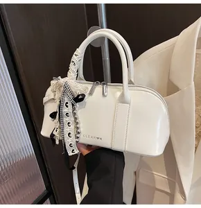 Detalle del bolso blanco con colgante de encaje y cremalleras metálicas plateadas