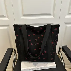 Large black corduroy tote bag with red strawberry print and wide strap handles