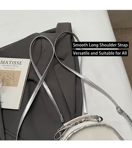 Detail der weißen runden Tasche mit silberner Kette neben grauem Blazer und Kunstbuch