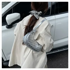 Detail of silver crescent hobo bag with metallic studs and glossy shoulder strap