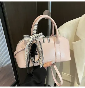 Detalle de bolso bandolera rosa claro con cinta de cuadros y doble cierre de cremallera