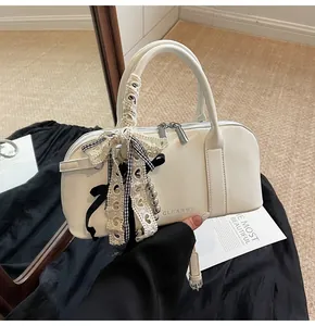 Detalle de bolso crema en cuero con lazo de encaje y letras de la marca CLEAROK