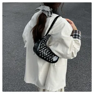 Detail of black crescent shoulder bag with silver studs worn with a white shirt
