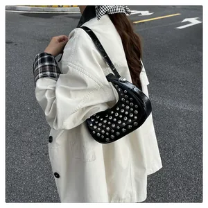 Outdoor street shot of a black crescent moon bag with silver metal stud decorations
