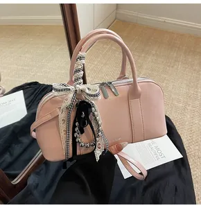 Detalle del bolso bandolera de cuero rosa claro con cremalleras plateadas y adorno de encaje