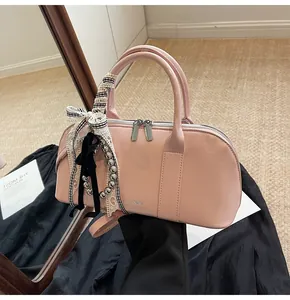 Bolso rosa semiovalado con cintas, perlas y lazos sobre un fondo de tela suave
