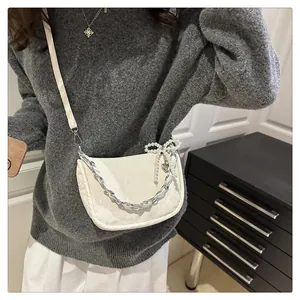Creamy white half-moon crossbody bag with silver chain and pearl bow detail