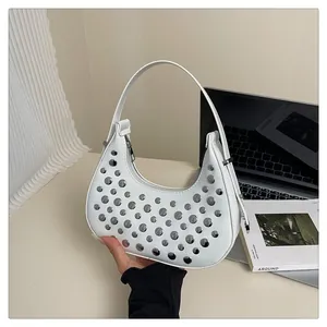 Detail of white half-moon bag featuring metallic rivet studs and urban punk aesthetic