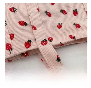 Detail of pink corduroy tote bag showing red strawberry prints and precision stitching