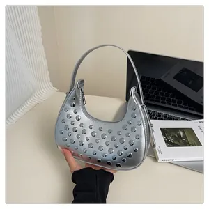 Detail of silver metallic hobo bag with polished rivets and smooth mirror finish texture