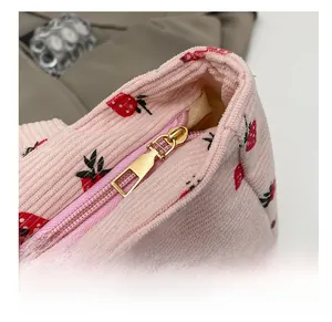 Close-up of pink corduroy tote bag with strawberry print and smooth golden zipper