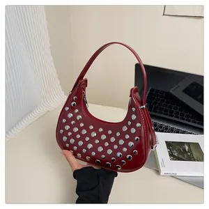 Detail of burgundy moon bag featuring silver metal rivets and sleek zipper closure