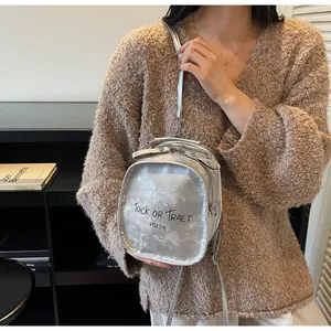 Detail eines silbernen Metallic-Minirucksacks mit Trick or Treat Aufdruck am Pelzpullover