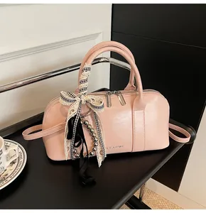 Detalle de bolso Boston rosa claro con lazo de cuadros y accesorios de cuentas finas