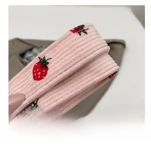 Detail of pink corduroy shoulder strap featuring cute red strawberry prints and soft texture