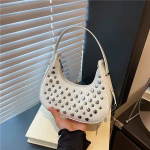 White crescent moon bag with silver studs and chic minimalist leather shoulder strap