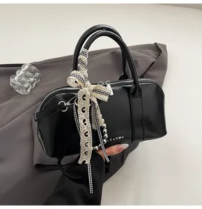 Primer plano del bolso de hombro negro brillante con adorno de lazo de encaje sutil