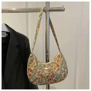 Detailed side view of floral tapestry underarm bag hanging with golden metal logo plaque