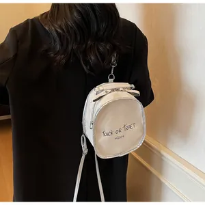 Detailansicht eines weißen Mini-Rucksacks mit schwarzer Schrift und silbernen Metallbeschlägen