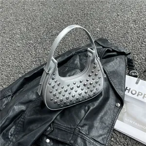 Silver crescent moon bag with metallic rivets and shoulder strap on leather jacket