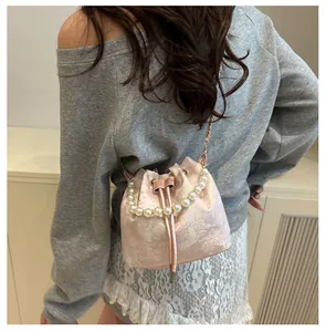 Detail of pink jacquard bucket bag with pearl handle and drawstring on a model