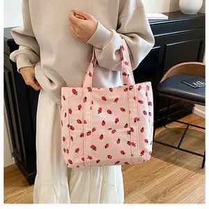 Detail of pink corduroy tote bag with strawberry pattern and convenient front pocket