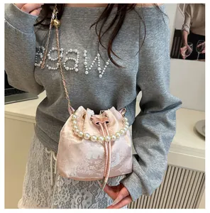 Detail of pink satin bucket bag with floral jacquard pattern and large pearl handle