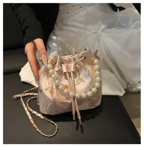 Close-up of pink silk bucket bag with gold floral embroidery and pearl handle detail