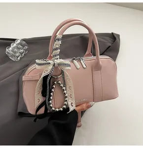 Detalle de bolso rosa con lazo de encaje y colgante de perlas decorativo