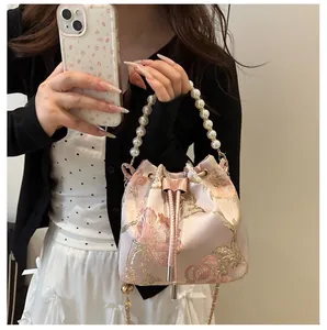 Detailed embroidery and pearl handle on a pink floral satin drawstring bucket bag