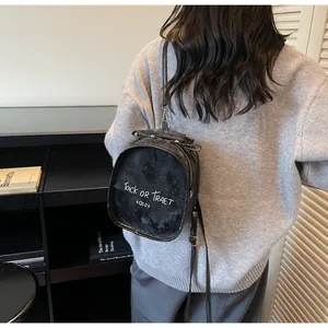 Detail eines schwarzen Kunstleder Rucksacks mit weißem Aufdruck und silbernen Reißverschlüssen