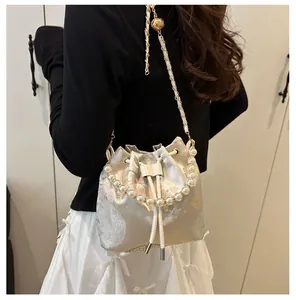 Detailed view of the drawstring bucket bag featuring pearl handle and floral embroidery