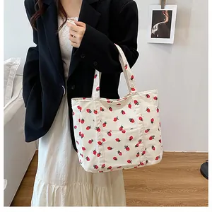 Detail view of white corduroy tote bag with red strawberry print on the front pocket
