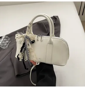 Detalle de bolso blanco de cuero sintético con lazo de encaje, cinta de seda y cuentas