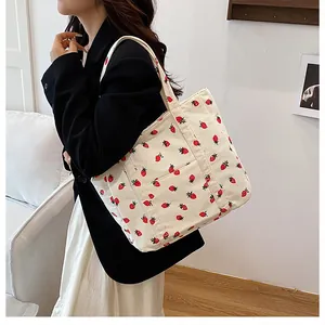 Detail of cream corduroy tote bag featuring red strawberry print and wide strap design