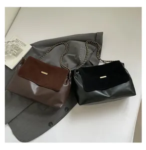 Detail view of contrast color chain bag featuring suede texture flap and metal logo plate
