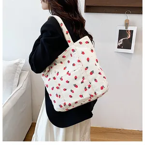 Detail of white corduroy tote bag featuring vibrant strawberry print and wide strap